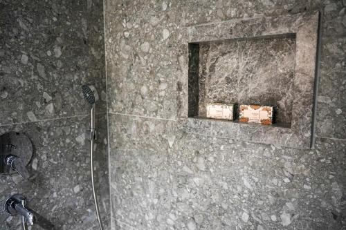 a bathroom with a shower with a stone wall at SOHO Residence in Selcuk