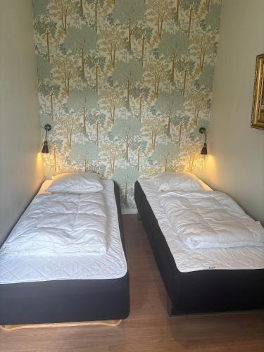 two beds in a room with a wallpaper with trees at Djursland Lystrup Strand Ferieboliger in Allingåbro