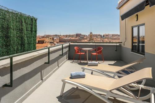 a balcony with two chairs and a table on a roof at Catalonia Plaza Mayor Salamanca in Salamanca