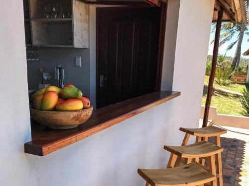 a bowl of fruit sitting on a counter with two stools at Ventos do Mar Lodge in Inhambane