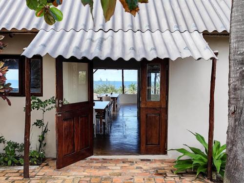 a house with a wooden door and a dining room at Ventos do Mar Lodge in Inhambane