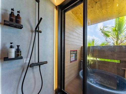 a bathroom with a shower with a tub and a window at Livemax Resort Inami Seafront in Inami