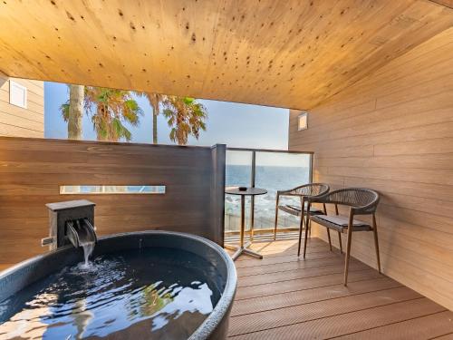 a hot tub in a room with a view of the ocean at Livemax Resort Inami Seafront in Inami