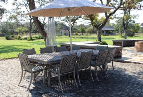 a table and chairs with an umbrella on a patio at Die Boskamp Self-Catering Bush Retreat in Marble Hall