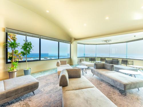 a living room with large windows and couches at Livemax Resort Inami Seafront in Inami