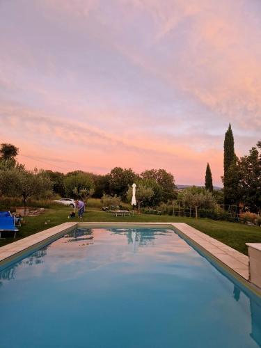 a swimming pool with a sunset in the background at Casale Il Fontanello in Todi