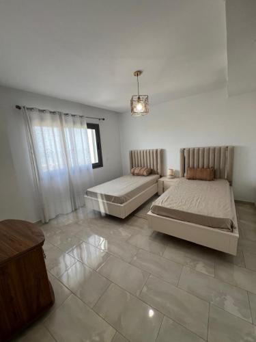 Un dormitorio grande con dos camas y una mesa. en 2BR Haut Standing Avec Piscine Face Hôtel Movenpick Sousse, en Sousse