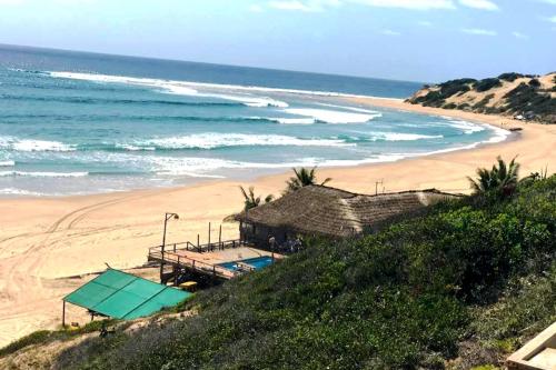 a beach with a building on a hill next to the ocean at Ventos do Mar Lodge in Inhambane