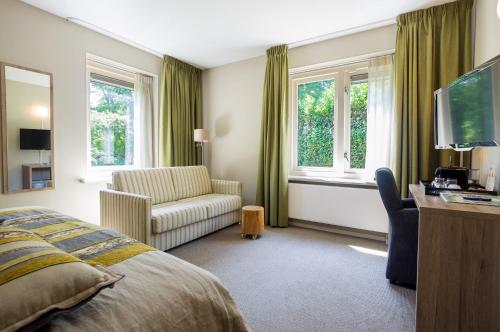 a bedroom with a bed and a chair and windows at Landgoedhotel Woodbrooke Barchem in Barchem