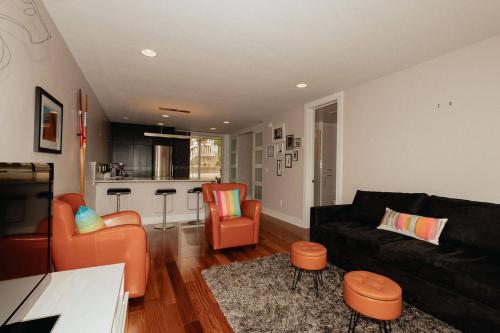 a living room with a black couch and orange chairs at Saugatuck Waterfront Getaway Shop, Eat, Bike, Pool in Saugatuck