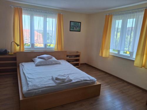 a bedroom with a bed with yellow curtains and windows at Chatka przy kapliczce in Bugaj