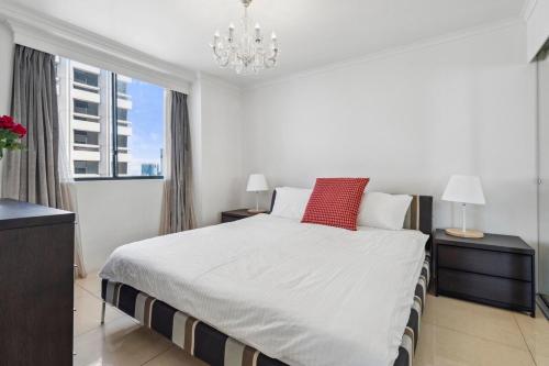 a white bedroom with a large bed and a chandelier at 92AH Abnb-Style Central Sydney 1BR, Free Parking, Prime Location in Sydney