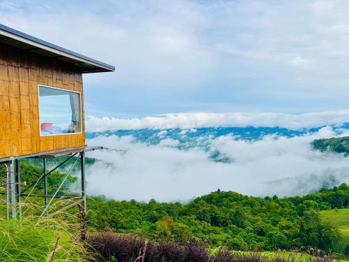 a house on a hill with a view of the clouds at ชิวชิวแคมป์ ภูชี้ฟ้า in Ban Huai Han