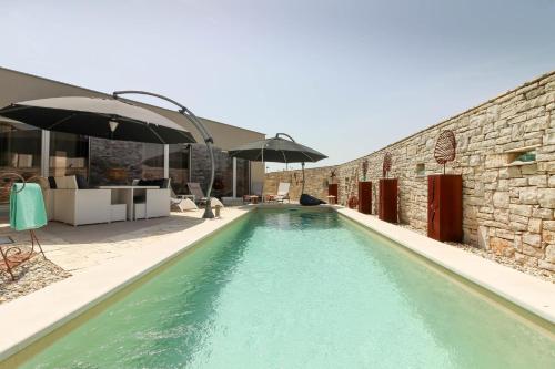 a swimming pool next to a building with an umbrella at Ferienhaus mit Privatpool für 6 Personen ca 130 qm in Kanfanar, Istrien Binnenland von Istrien in Kanfanar