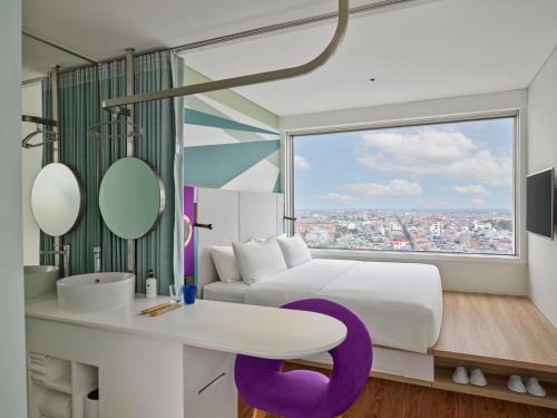a bedroom with a white bed and a purple chair at Tru by Hilton Nam Dinh City Centre in Nam Ðịnh