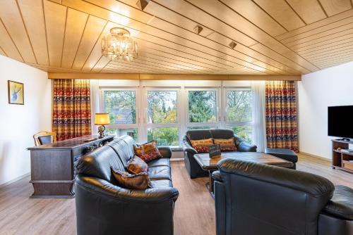 a living room with leather couches and a tv at Haus Wiesengrund - Hundefreundlich in Gammertingen