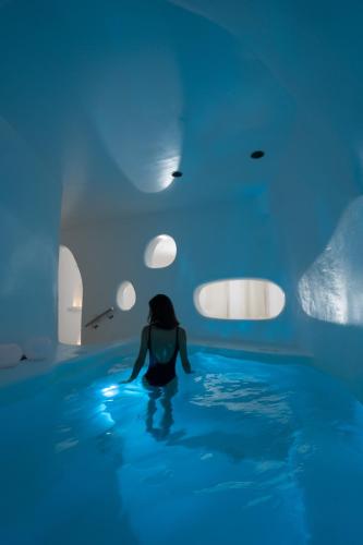 a woman in a swimming pool with blue lights at Hotel Goulielmos in Akrotiri