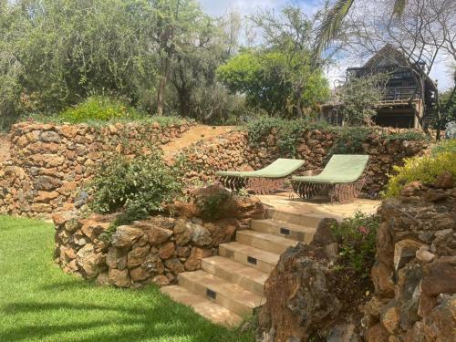 a garden with two benches and a stone wall at O'Leleshwa Retreat in Naivasha