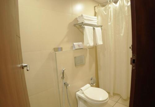 a bathroom with a toilet and a shower with towels at Queens Hotel in Kozhikode