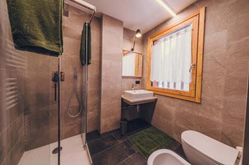 un bagno con doccia, lavandino e WC di Ciasa Nü - Piano Rialzato a Pozza di Fassa