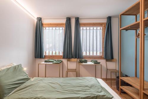 una camera con un letto e due tavoli e due finestre di Ciasa Nü - Piano Rialzato a Pozza di Fassa