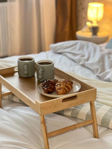 a wooden tray with two cups of coffee and pastries on a bed at Panorama Piaskowa in Wałbrzych
