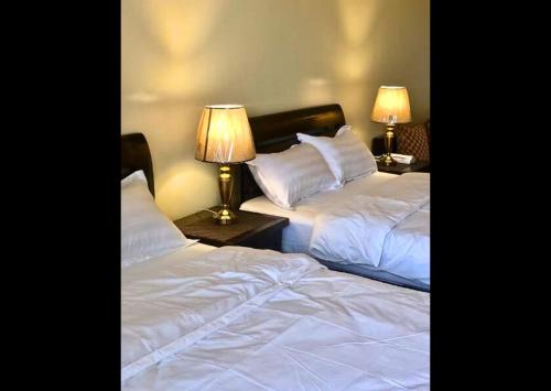 duas camas num quarto de hotel com duas lâmpadas em Need Place To Stay Wake Up to Breathtaking Taal Views from Your Window I Tagaytay Getaway em Kaybagal