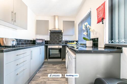 a kitchen with white cabinets and black counter tops at Severn Street House Serviced Accommodation in Leigh