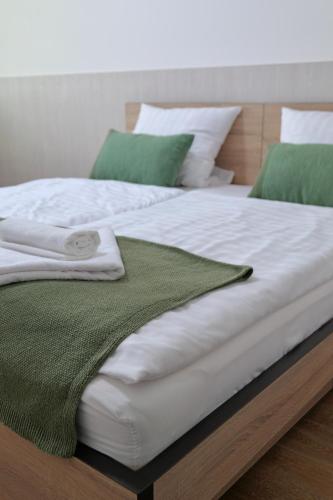a white bed with green and white sheets and pillows at Hotel Venatus in Zalaegerszeg