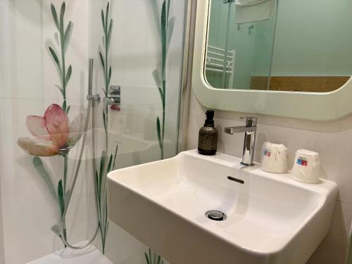 a white bathroom with a sink and a mirror at Sciclintorno in Scicli