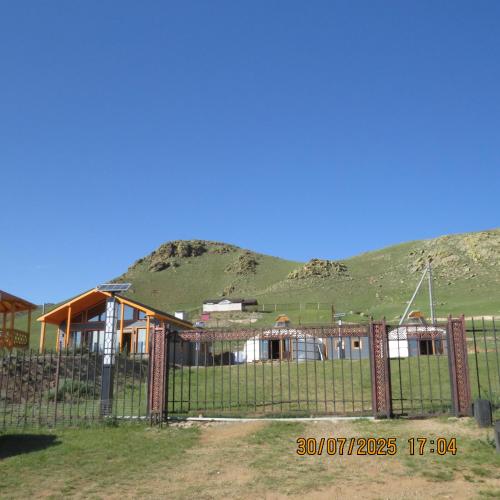a house with a fence in front of a mountain at Bright Terelj Family Camp in Dugang Süme