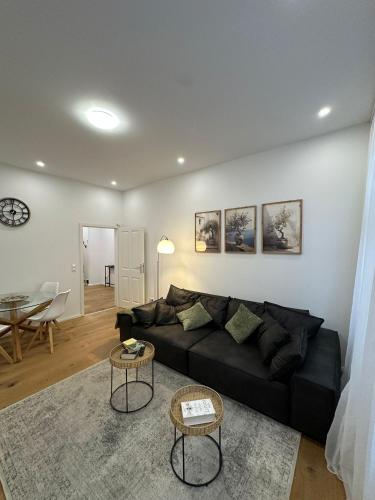 a living room with a black couch and a table at Nook - Zentrale Lage - an der ListerMeile in Hannover