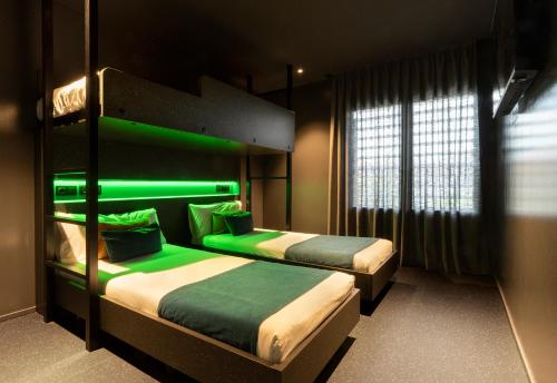 two beds in a room with green lighting at AMISTAT City Hostel Barcelona in Barcelona