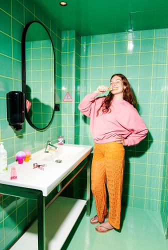 a woman standing in a bathroom brushing her teeth at AMISTAT City Hostel Barcelona in Barcelona