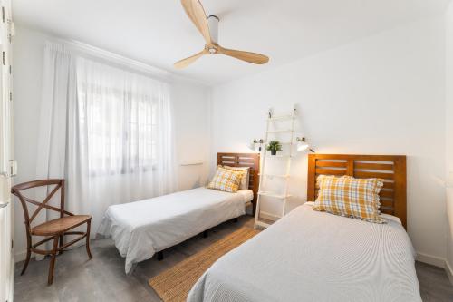 une chambre avec deux lits et un ventilateur de plafond dans l'établissement Casa Keiley by EscapeHome, à Puerto del Carmen