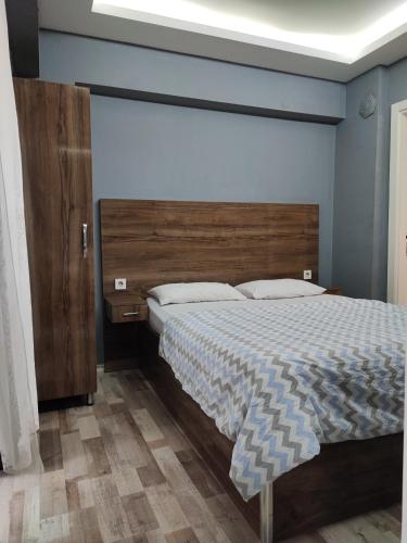 a bedroom with a large bed with a wooden headboard at Smyrna Homes & Suits in Konak