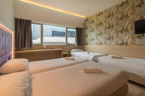 a hotel room with two beds and a tv at Hotel Antares Sport Beauty & Wellness in Villafranca di Verona