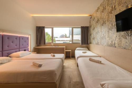 a hotel room with two beds and a tv at Hotel Antares Sport Beauty & Wellness in Villafranca di Verona