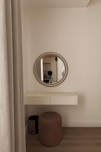 a round mirror on a white wall with a stool at The World Hotel in Móng Cái