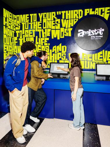 a group of people standing around a counter with a laptop at AMISTAT City Hostel Barcelona in Barcelona
