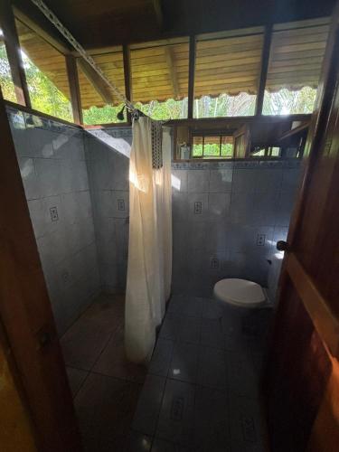 a bathroom with a toilet and a shower curtain at Sabalo Lodge Tours and Cabins in Sierpe