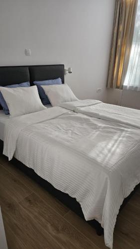 a large bed with white sheets and blue pillows at Memento Ljubljana apartment 2-4 in Ljubljana