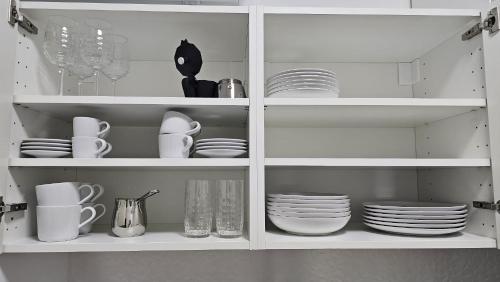 a white cabinet filled with plates and dishes at Memento Ljubljana apartment 2-4 in Ljubljana