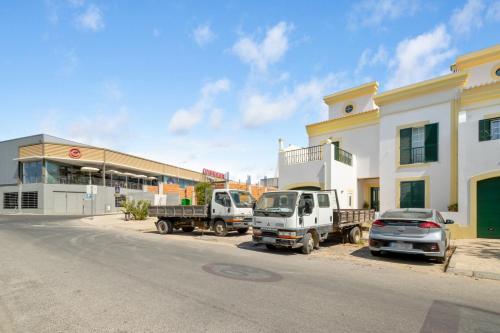 two trucks and a car parked in front of a building at Mae Joana pool&beach Faro villa in FAO