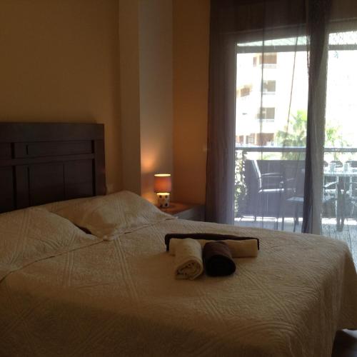 a bedroom with a bed with two towels and a window at Benidorm La Cala Sidney in Cala de Finestrat