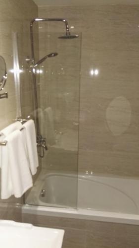 a bathroom with a shower and a bath tub with towels at P Quattro Relax Hotel in Wadi Musa