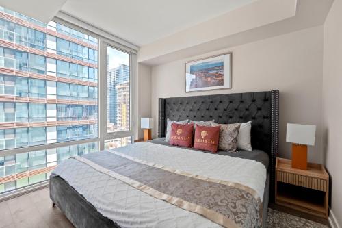 a bedroom with a large bed and a large window at Bright 1BD & Den in Downtown Toronto in Toronto