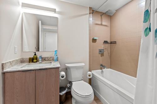 a bathroom with a toilet and a sink and a tub at Bright 1BD & Den in Downtown Toronto in Toronto