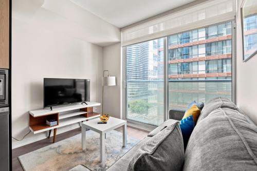 a living room with a couch and a large window at Bright 1BD & Den in Downtown Toronto in Toronto