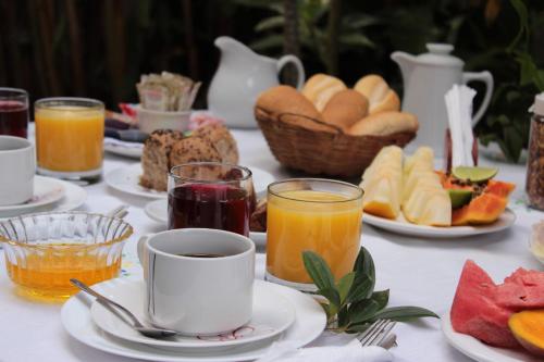 a table with plates of food and glasses of orange juice at Pouso Mel de Liz in Paraty